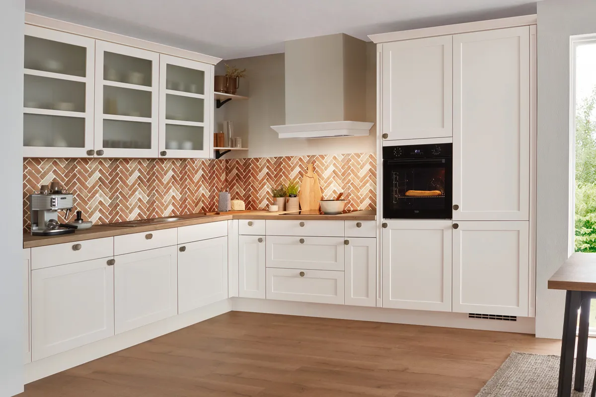 Landhausküche in Magnolia mit Rahmenfronten, Glasvitrinen und Fischgrät-Fliesenspiegel